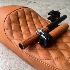 a close up of a brown leather seat with two black handlebars on it