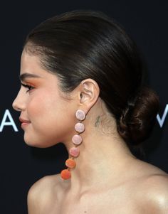 a close up of a person wearing earrings with hair in a bun and earrings