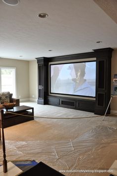 an empty living room with a large screen in the middle and no curtains on the floor