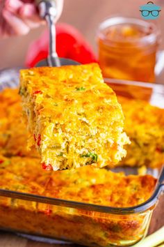 someone is lifting a piece of quiche out of the casserole dish with a fork