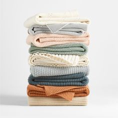 a stack of folded sweaters and scarves on top of each other in different colors