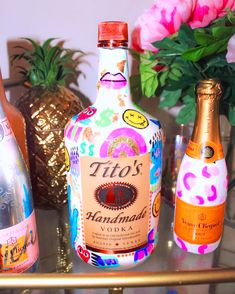 three bottles of liquor sitting on top of a metal shelf next to flowers and vases