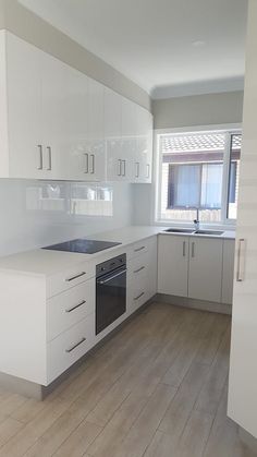 an empty kitchen with all white cabinets and wood flooring is seen in this image