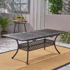 an outdoor patio table sitting on top of a rug next to a potted plant