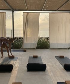 a woman is practicing yoga in front of an open air area with large windows overlooking the ocean