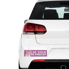 the back end of a white car with a pink sticker that says use your blinker