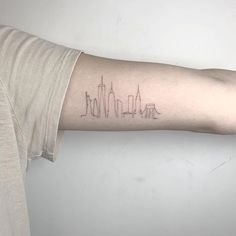 a person's arm with a city skyline tattoo on the left side of their arm