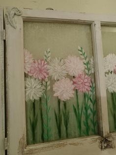 some pink and white flowers are painted on an old window sill with green stems