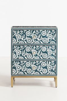 a blue and white dresser with flowers painted on it