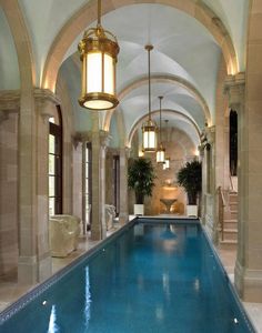 a large indoor swimming pool in the middle of a room with columns and arches on either side