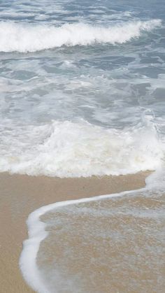 an ocean view with waves coming in to shore and a person walking on the beach