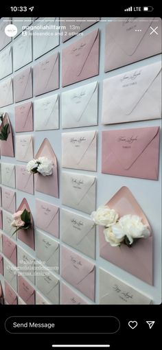 some pink and white envelopes on a wall with flowers attached to the back of them