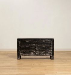 an old black dresser sitting on top of a hard wood floor next to a white wall