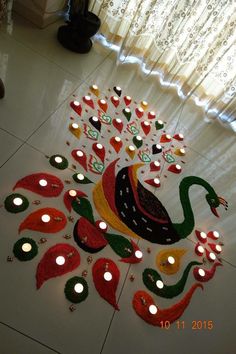 candles are lit on the floor in front of a peacock made out of colored paper