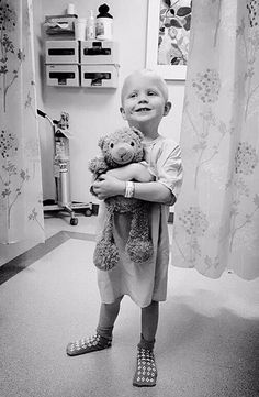 a little boy that is holding a teddy bear in his arms and smiling at the camera