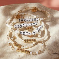 four bracelets with words on them sitting on top of a white cloth covered rock