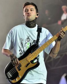 a man holding a guitar on stage with his mouth open and piercings around his neck