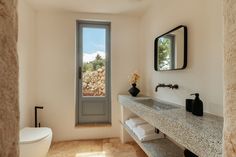 a bathroom with two sinks, a toilet and a large window in the wall next to it