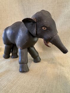 an elephant figurine sitting on top of a white cloth covered floor next to a wall