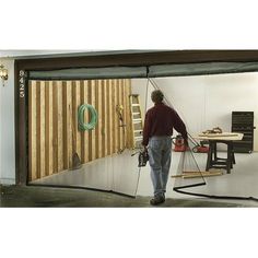 a man standing in front of a garage door holding a power drill and an extension cord