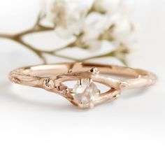 a close up of a ring on top of a branch with flowers in the background