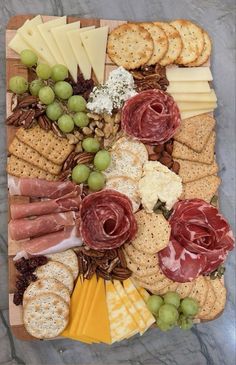 an assortment of cheeses, crackers and meats on a wooden platter