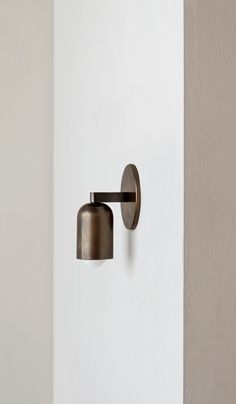 a wall mounted light on the side of a white wall next to a gray door