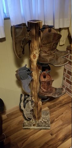 several pairs of shoes are stacked on a wooden pole in front of a window with white curtains