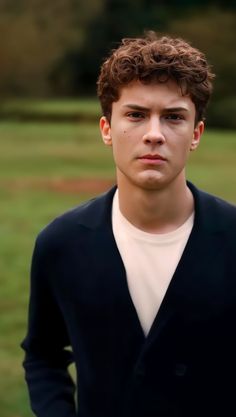 a young man standing in front of a green field