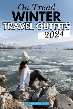 a woman sitting on rocks next to the water with text that reads, on trend winter travel outfits 2021