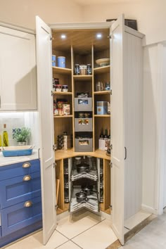 an open pantry in the middle of a kitchen with blue cabinets and white counter tops