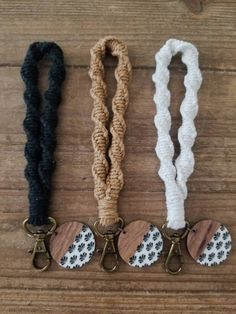 three different types of lanyards on a wooden table with one black, one white and one brown