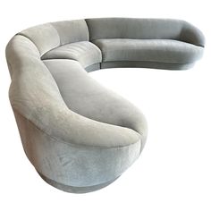 the curved couch is made out of grey fabric and has a rounded back rest on it's side