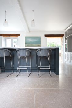 two bar stools sit at the end of a kitchen island in an open floor plan