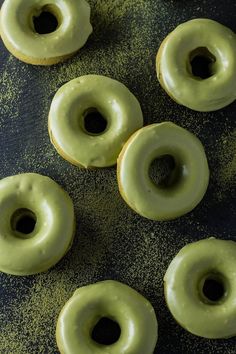 green frosted donuts sitting on top of a black table next to each other