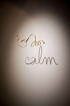 the word calm written in cursive writing on a wall