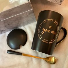 a black coffee mug with the words you are on it next to a spoon and box