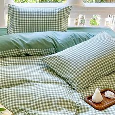 a green and white checkered comforter on a bed with sea shells in a tray