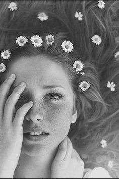 a woman with red hair and daisies on her head is looking at the camera