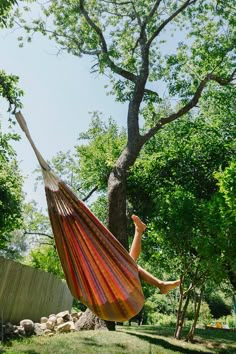 a woman laying in a hammock with her feet up on the ground next to a tree