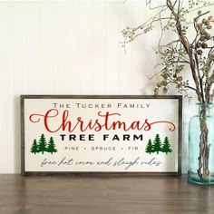 a christmas tree farm sign sitting on top of a table next to a vase filled with branches