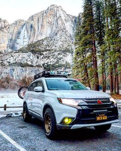 a white car parked in front of a mountain with snow on it's ground