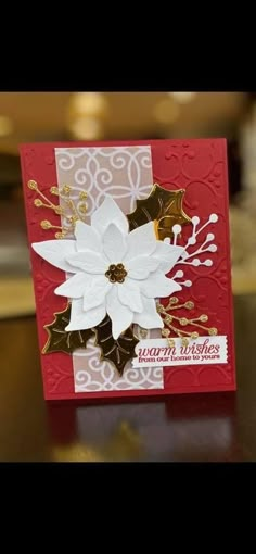 a red and white christmas card with poinsettis on the front, gold trim around the edges