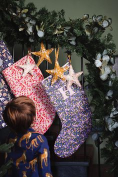 a little boy looking at three christmas stockings