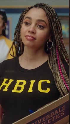 a woman with dreadlocks holding a book in her hand and looking at the camera