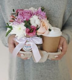 a person holding a cup with flowers in it and a ribbon around the bottom that says grandma's coffee