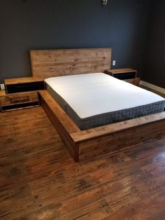 a bed with a wooden headboard and night stand in a room that has hard wood flooring