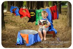 a young boy sitting on a bench reading a book in front of clothes hanging from a line