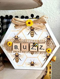 a wooden block with the word buzz spelled on it next to some flowers and bees