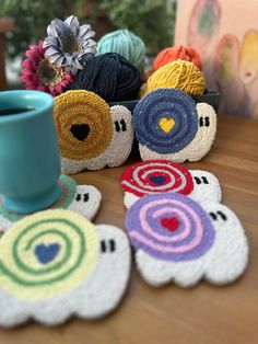 several crocheted coasters with different designs on them and a coffee cup in the middle